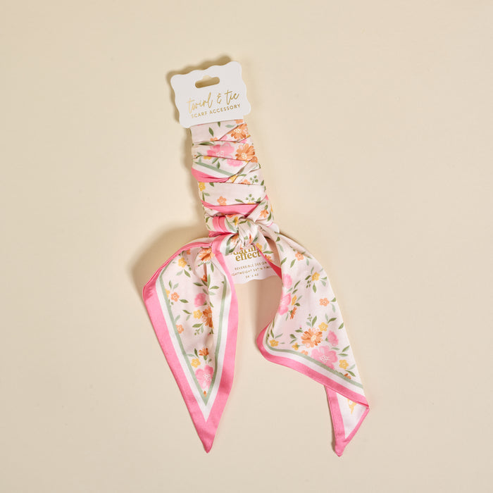 The Darling Effect's Endless Daydream Cream Twirl & Tie Scarf Accessory features a pink and white floral scrunchie with a versatile scarf detail, shown on a cream background. The tag reads "Twirl & Tie Scarf Accessory." Ideal for endless styling options.