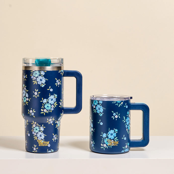 Two Endless Daydream Navy 14 oz Insulated Mugs by The Darling Effect, featuring handles, clear lids, and light blue floral patterns, sit side by side on a white surfaceโperfect for keeping your coffee hot with double-wall insulation.