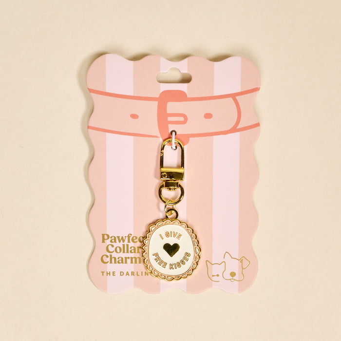 The Darling Effect’s Free Kisses Pawfect Collar Charm is a gold keychain with a round I give free kisses charm, on pink packaging with a drawn collar and cat—perfect for playful pet style and your pet collar charm collection.