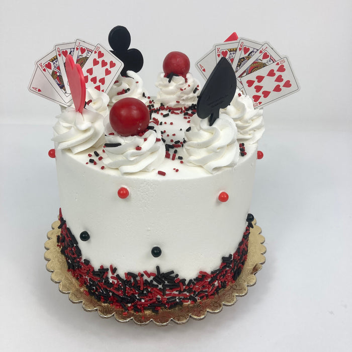 White Let's Gamble Cake decorated with red and black gumballs, playing card suits, and playing cards on top