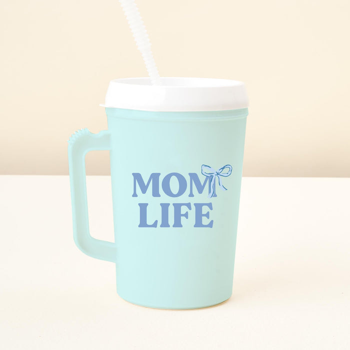 The-darling-effect's Mom Life 34oz Mega Mug is a light blue tumbler with a white lid and straw, decorated with "MOM LIFE" in dark blue text and a small bow.
