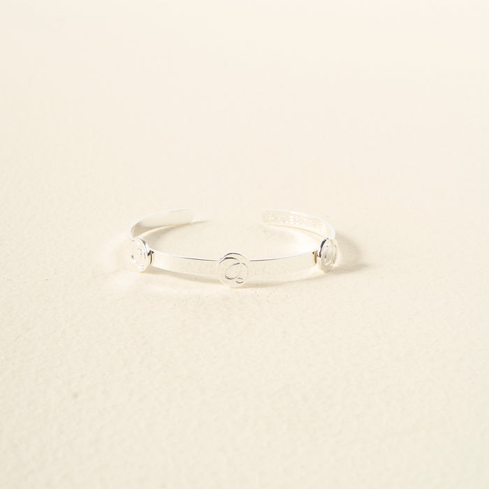 The Darling Effect's You Are Sassy Skinny Stacker Bracelet is a thin, silver adjustable cuff with three evenly spaced circular accents, shown on a neutral, light background.