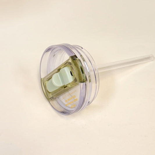 The Darling Effect’s 20 oz Green Lifestyle Flip Straw Replacement Lid features a clear plastic design with a sliding white closure, leak-resistant seal, and attached transparent straw, shown against a plain white background.