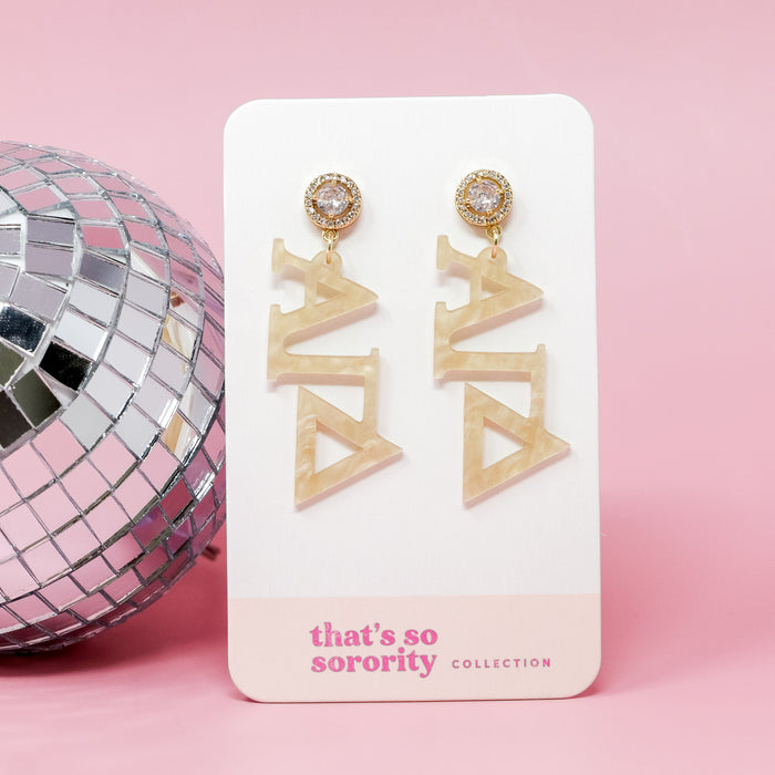 Alpha Gamma Delta Letter Gold Acrylic Earrings by The Darling Effect, shown on a branded card against a pink background with a silver disco ball—perfect for sisterhood events or as a fun addition to any bid day basket.