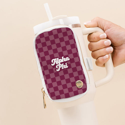 A hand holds a large white tumbler with The Darling Effect’s Alpha Phi Tumbler Fanny Pack, featuring a maroon and pink checkered pattern and “Alpha Phi” in white script, attached to the handle.