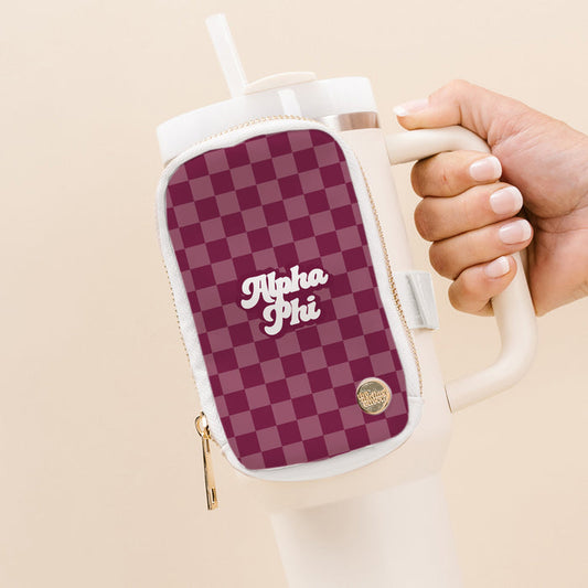 A hand holds a large white tumbler with The Darling Effect’s Alpha Phi Tumbler Fanny Pack, featuring a maroon and pink checkered pattern and “Alpha Phi” in white script, attached to the handle.