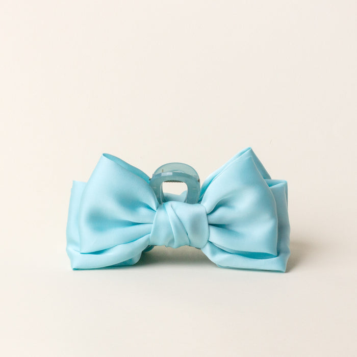The Aqua Satin Bow Claw Clip by the-darling-effect is a chic hair accessory, bow-shaped and perfect for updos, shown against a plain off-white background.