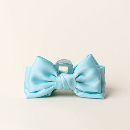 The Aqua Satin Bow Claw Clip by the-darling-effect is a chic hair accessory, bow-shaped and perfect for updos, shown against a plain off-white background.