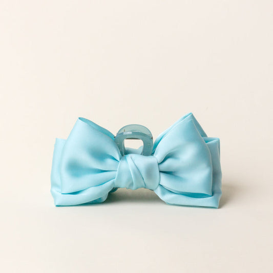 The Aqua Satin Bow Claw Clip by the-darling-effect is a chic hair accessory, bow-shaped and perfect for updos, shown against a plain off-white background.