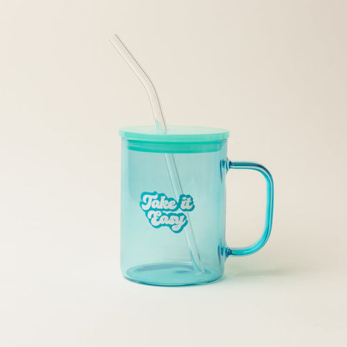 The Darling Effect’s Aqua Take it Easy Color Glass Mug with Handle features a translucent blue body, teal lid, clear glass straw, and “Take it Easy” text in white and blue.