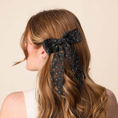 A woman's back is shown with wavy auburn hair pulled back by the-darling-effect's Black Ditzy Daisies Hair Bow, featuring delicate floral details and a gold barrette clip for an elegant finish.