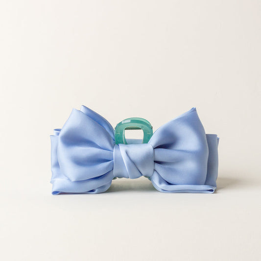 The-darling-effect's Blue Satin Bow Claw Clip features a large light blue satin bow on a translucent green clip—perfect for elegant updos. Shown against a plain white background.