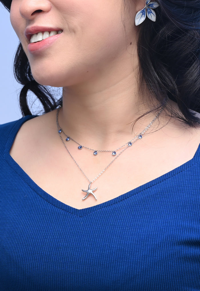 Woman wearing a starfish necklace and blue top against a light blue background