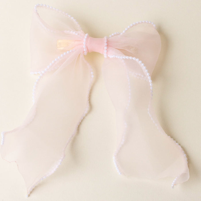 The-darling-effect's Blush Sheer Pearl Hair Bow features sheer pink fabric, a satin center, and a pearl-trimmed border—an elegant addition to your hair accessories collection.