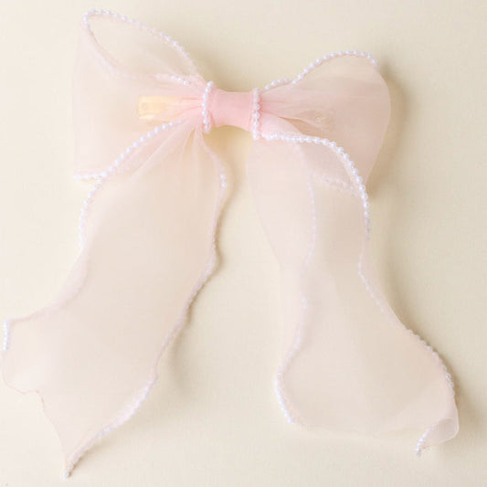The-darling-effect's Blush Sheer Pearl Hair Bow features sheer pink fabric, a satin center, and a pearl-trimmed border—an elegant addition to your hair accessories collection.