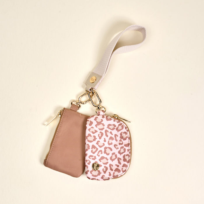 The Darling Effect’s Born Wild Dynamic Duo Pouch Wristlet features a small pink pouch with beige leopard print, gold zipper, mauve side pocket, and beige strap—perfect for zippered pouch fans. Photographed on a light background.