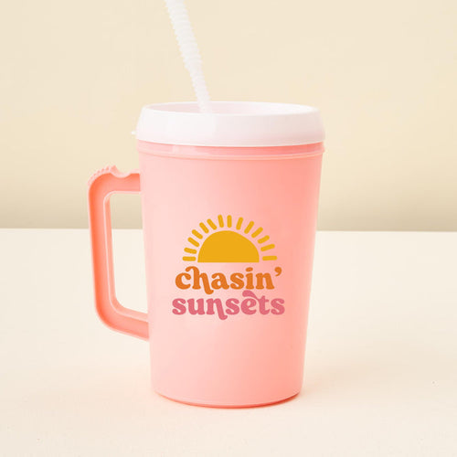 The-darling-effect’s Chasin' Sunsets 34oz Mega Mug is a large pink plastic tumbler with handle, white lid, straw, sun graphic, and "chasin sunsets" in yellow and pink—perfect event drinkware for any occasion.