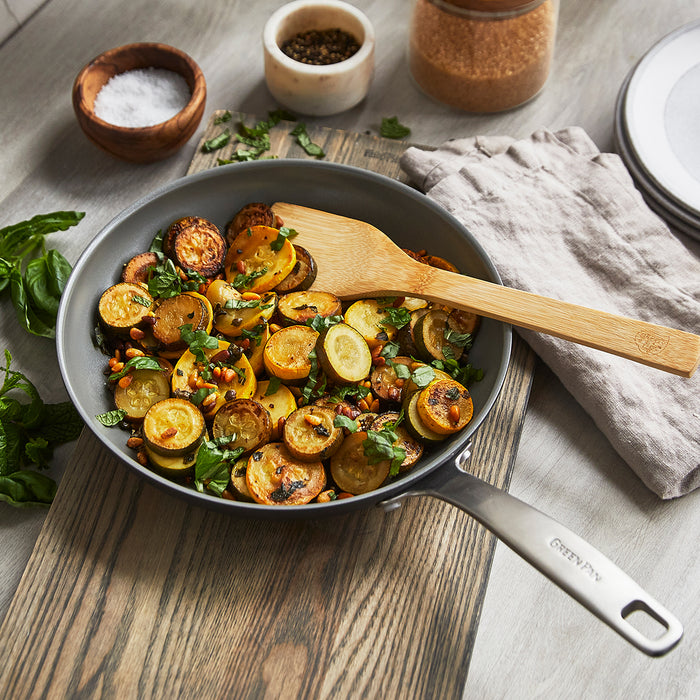 Vegetables with herbs cooking in Chatham ceramic nonstick cookware set on a kitchen counter.