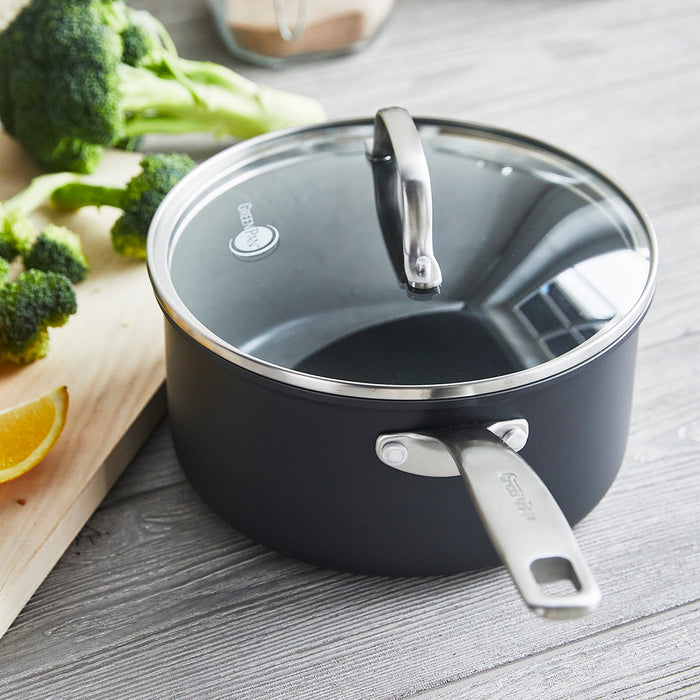 Ceramic nonstick 3-quart saucepan with lid on wood surface, next to broccoli and a lemon wedge.