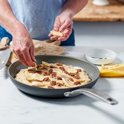 Banana slices and pecans being added to batter in an 8-inch ceramic nonstick frypan.