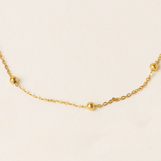 The Chloe Beaded Necklace Chain by the-darling-effect features a delicate gold chain with small gold beads spaced along its length, shown on a plain light background—making it a versatile accessory for any occasion.