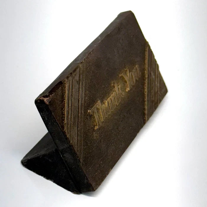 A side view of an elegant rectangular chocolate favor features rich brown finish accented with a delicate touch of gold dust for a luxurious shimmer. Subtle diagonal lines frame the design, while the words “Thank You” are gracefully embossed in the center.
