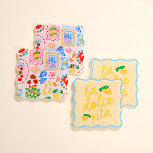 The Darling Effect's Ciao Bella Table Talk Acrylic Coaster Set includes two stylish designs—Italian coastal motifs and yellow lemon “la dolce vita”—making them perfect for chic table décor.