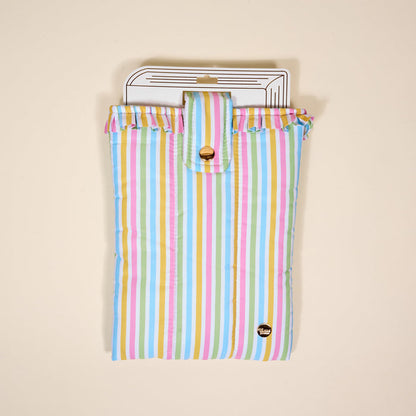 The Darling Effect’s Color Me Happy Book Cover features pastel stripes, ruffled edges, and a gold snap closure—a cute puffy polyester pouch that protects your books in style.