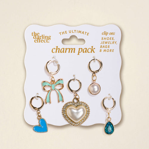 The Darling Effect’s Coquette Cloud The Ultimate Charm Pack features six gold-tone clip-on charms—blue bow, pearl, rhinestone heart, blue heart, clear blue teardrop, and round stone—perfect for scrunchie sets or statement necklaces.