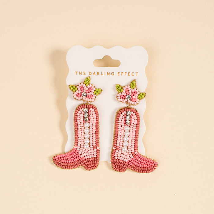 The Darling Effect Cowgirl Boot Beaded Earrings feature pink hand-beading, pearls, rhinestones, and floral details—perfect for adding a playful touch to your jewelry collection.