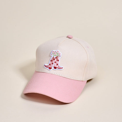 The Darling Effect Cowgirl Boots Classic Canvas Hat in beige and pink features a relaxed fit and a front embroidered patch of pink cowboy boots with flowers, shown on a light neutral background.