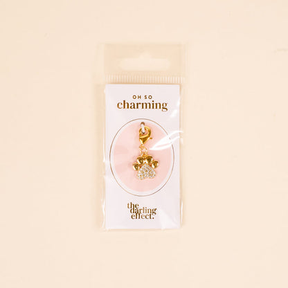 The Darling Effect's Dazzled Paw Print Jewelry Charm Gold features a rhinestone-studded paw design on an OH SO charming card, packaged in a clear sleeve—perfect for adding sparkle to any charm bar collection.