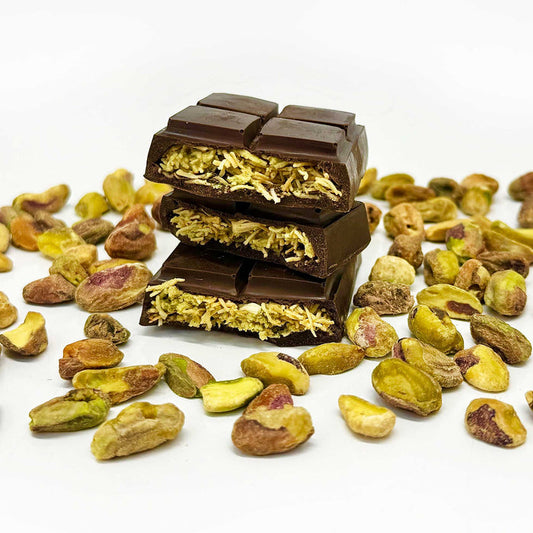 Three pieces of the Dubai Chocolate bar that's  filled with pistachio cream, tahini, and crispy kataifi dough, are stacked on top of each other