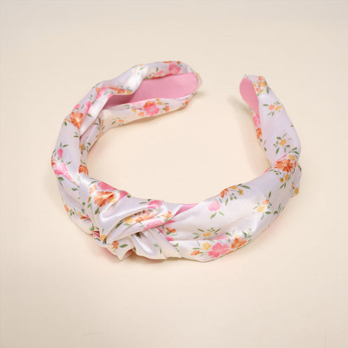 The Darling Effect’s Endless Daydream Cream Classic Twist Headband features a floral print with a chic knot design, shown on a light beige background—a versatile accessory perfect for any occasion.