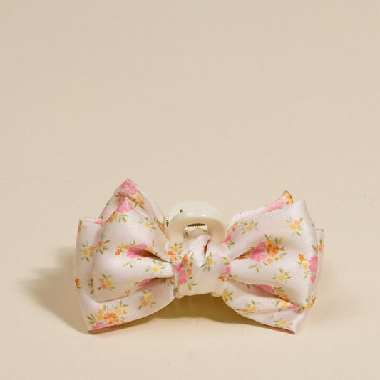 The Darling Effect Endless Daydream Cream Mini Satin Bow Claw Clip features a bow shape and delicate satin with a pink, yellow, and orange floral print.