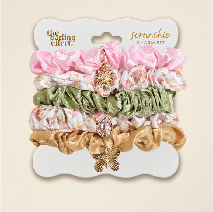 The Darling Effect’s Endless Daydream Cream Scrunchie Charm Set features four stylish hair accessories—pink, green floral, white floral, and gold—each with a unique charm, displayed on a branded card.