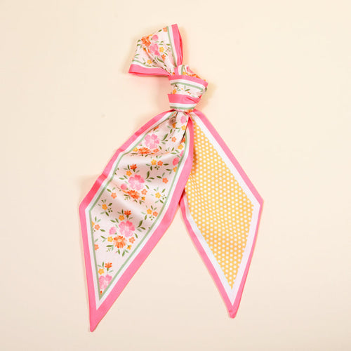The Darling Effect's Endless Daydream Cream Twirl & Tie Scarf Accessory is a versatile silk scarf with pink edges, floral print on one end, and yellow polka dots on the other, all set against a light beige background.