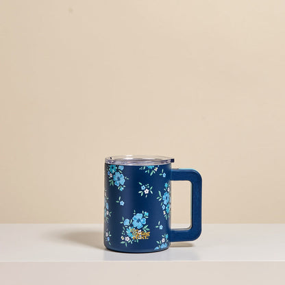 The Darling Effect's Endless Daydream Navy 14 oz Insulated Mug, featuring double-wall insulation, a clear lid, and light blue floral patterns, rests on a white surface against a beige background.
