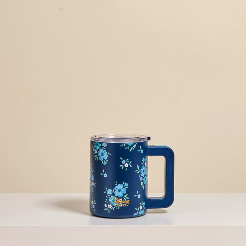 The Darling Effect's Endless Daydream Navy 14 oz Insulated Mug, featuring double-wall insulation, a clear lid, and light blue floral patterns, rests on a white surface against a beige background.