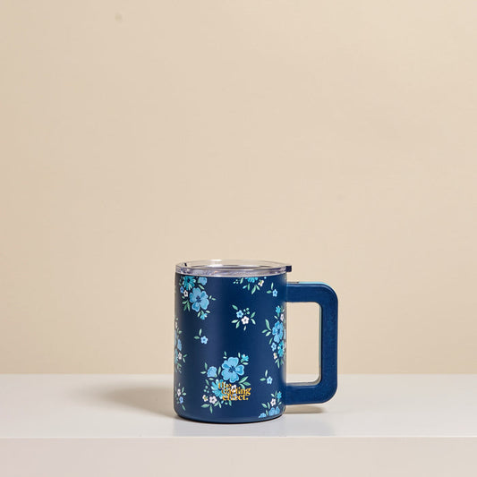 The Darling Effect's Endless Daydream Navy 14 oz Insulated Mug, featuring double-wall insulation, a clear lid, and light blue floral patterns, rests on a white surface against a beige background.