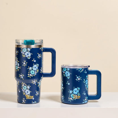 Two Endless Daydream Navy 14 oz Insulated Mugs by The Darling Effect, featuring handles, clear lids, and light blue floral patterns, sit side by side on a white surface—perfect for keeping your coffee hot with double-wall insulation.