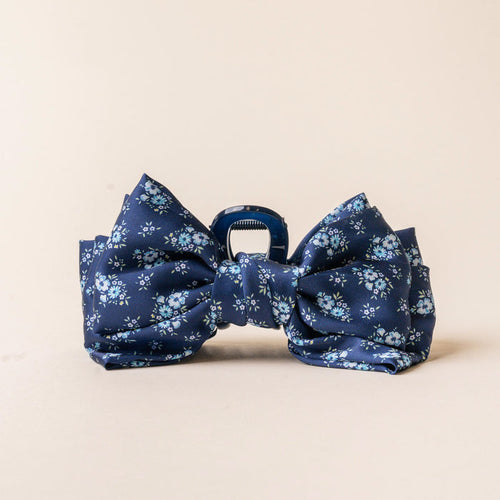 The Endless Daydream Navy Satin Bow Claw Clip by the-darling-effect features a floral pattern, making it a chic hair accessory for elegant updos.