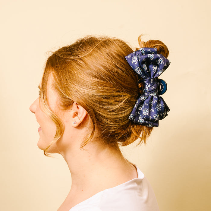 Side profile of a woman with blonde hair in an elegant updo, secured with the-darling-effect's Endless Daydream Navy Satin Bow Claw Clip.