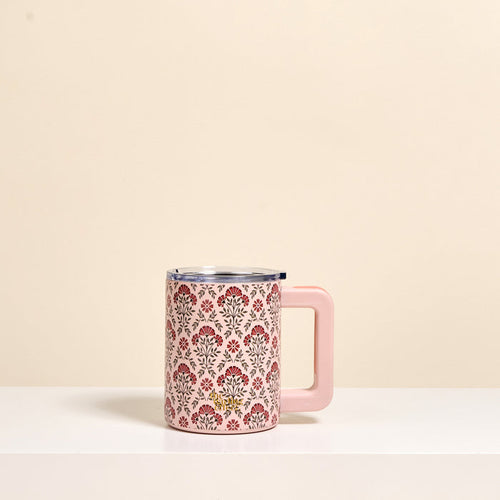 The Darling Effect's Everbloom Dusty Rose 14 oz Insulated Mug, featuring a pink handle and a floral pattern in red, pink, and brown, rests on a white surface against a beige background.