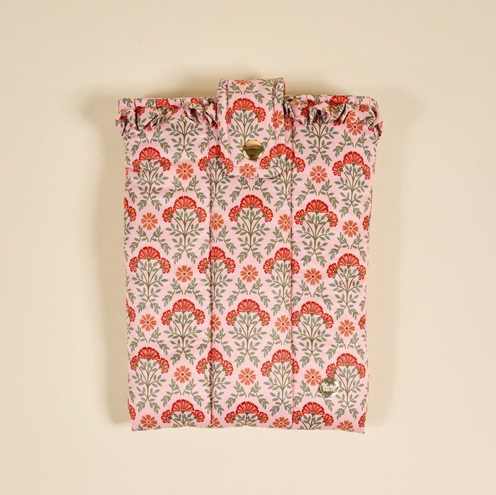 The Everbloom Dusty Rose Book Cover features a puffy polyester design with red and green floral patterns on a light pink background, a snap button flap closure, and is shown against a beige backdrop for stylish book protection.