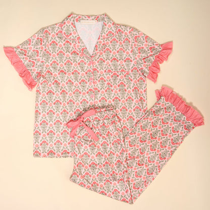 The Darling Effect Everbloom Dusty Rose Slumber Party Pajama Pants Set features a pink and gray floral print, collared button-up top, ruffled trim pants, and ultra-soft fabric, shown laid flat on a light background.