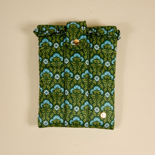 The Darling Effect's Everbloom Forest Green Book Cover features a green and blue floral pattern, snap button closure, and puffy polyester design, offering stylish protection for your book against a beige background.