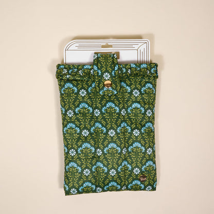 The Darling Effect's Everbloom Forest Green Book Cover features a green and blue floral pattern, folds with a button closure, and provides stylish book protection. It's shown on a light beige background with a white tag at the top.