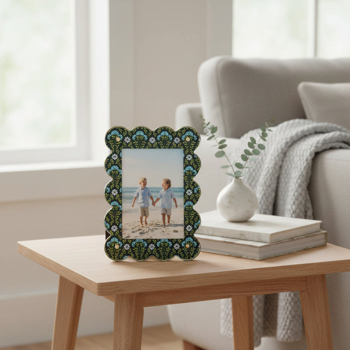 The Darling Effect’s Everbloom Forest Green Rectangle Scalloped Acrylic Picture Frame stylishly displays a photo of two young boys holding hands on a beach.
