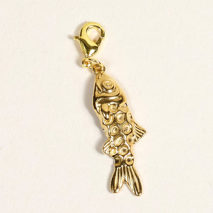 The Darling Effect Fish Jewelry Charm Gold features a textured, scale-like pattern and a lobster clasp, ideal for charm bars or layering necklaces. Shown against a plain light background.